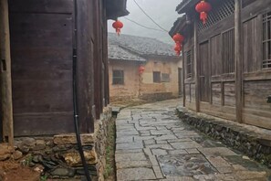 A narrow stone pathway between traditional wooden buildings with red lanterns. - Changting Peace Hotel (Changting)