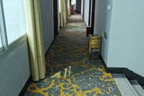 A hallway with a patterned carpet, a small table, and a door on the right. - Changting Peace Hotel (Changting)
