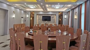 A conference room with a round table, multiple chairs, and a flat-screen TV mounted on the wall. - Changting Peace Hotel (Changting)
