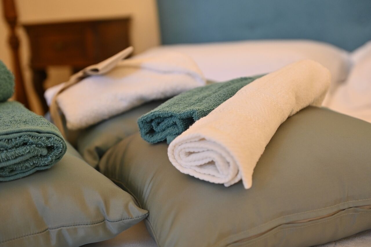 A neatly made bed with folded towels and pillows.