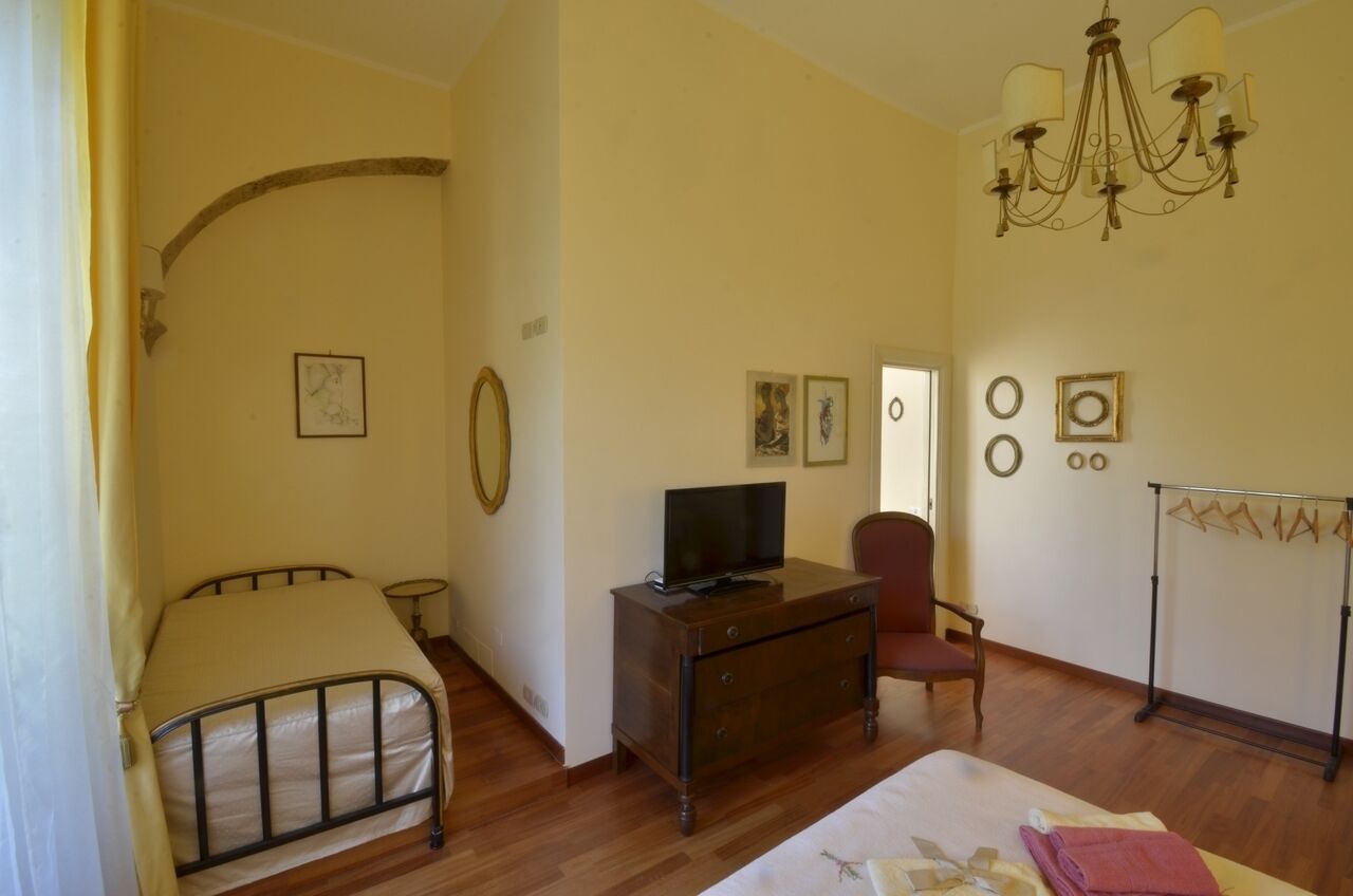 Quarto com cama, escrivaninha com televisão, cadeira e guarda-roupa.