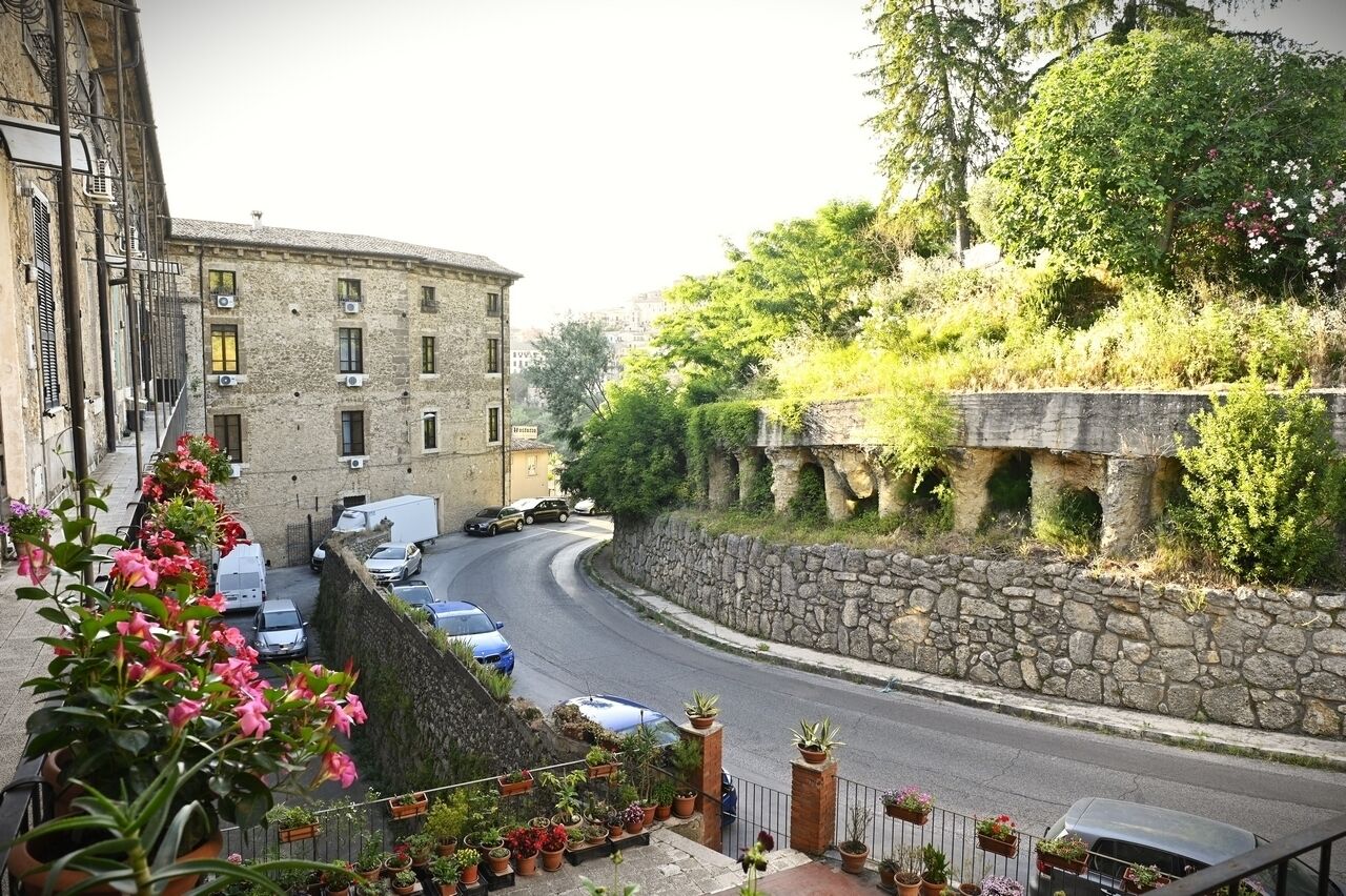 Une rue étroite, bordée d’un côté de voitures garées et de l’autre d’un mur de pierre.