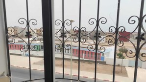 A balcony with ornate metal railings overlooking a street with buildings. - Apartment 5 minutes from Anza beach (Agadir)