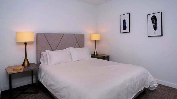 A hotel room with a bed, two bedside tables with lamps, and two framed pictures on the wall. - Authentic CB, Historic Remodeled Elk Ave Gem! (Crested Butte)