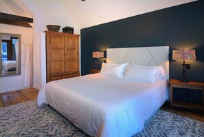A bedroom with a large bed, wooden wardrobe, and two bedside lamps. - Authentic CB, Historic Remodeled Elk Ave Gem! (Crested Butte)