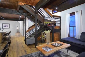 A modern interior with a staircase, a seating area with a sofa and a table, and a view of a stadium through a window. - Authentic CB, Historic Remodeled Elk Ave Gem! (Crested Butte)