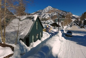 A snow-covered street with houses and a mountain in the background.