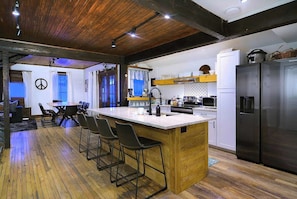A modern kitchen with a central island, bar stools, and stainless steel appliances.