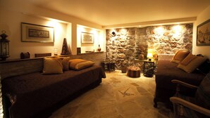 A cozy room with two sofas, a stone wall, and framed pictures on the walls. - Villa with pool and basketball court, pet friendly  (Thimari)