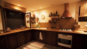 A kitchen with wooden cabinets, a stove, and a large window. - Villa with pool and basketball court, pet friendly  (Thimari)