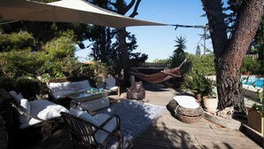 A wooden deck with outdoor furniture, a hammock, and a pool in the background. - Villa with pool and basketball court, pet friendly  (Thimari)