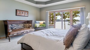 Ein Schlafzimmer mit einem großen Bett, einem Fernseher, einer Bank und Blick ins Freie.