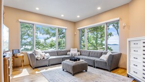 Ein modernes Wohnzimmer mit einem Ecksofa, einem Couchtisch und Blick auf einen See.