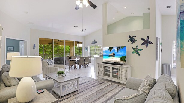 Un salón amplio con ventilador de techo, televisor y ventana grande con vistas a un jardín.