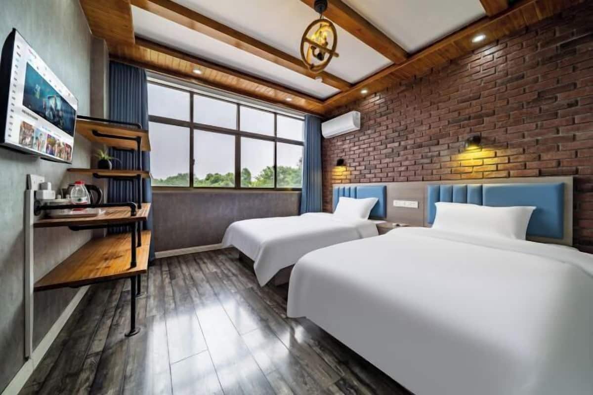 Ein Hotelzimmer mit zwei Betten, einem Schreibtisch mit Computer und einem großen Fenster.