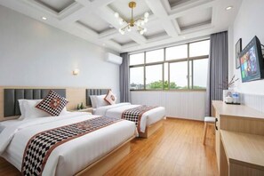 Habitación de hotel con dos camas, un escritorio, un ventanal grande y un techo con diseño geométrico.