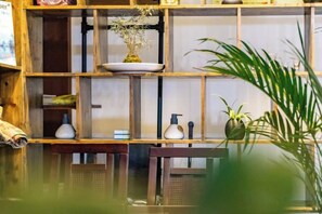 A room with a wooden bookshelf, a small table, and a potted plant. - Wuzhen Xizha Jiurige Homestay (Tongxiang)