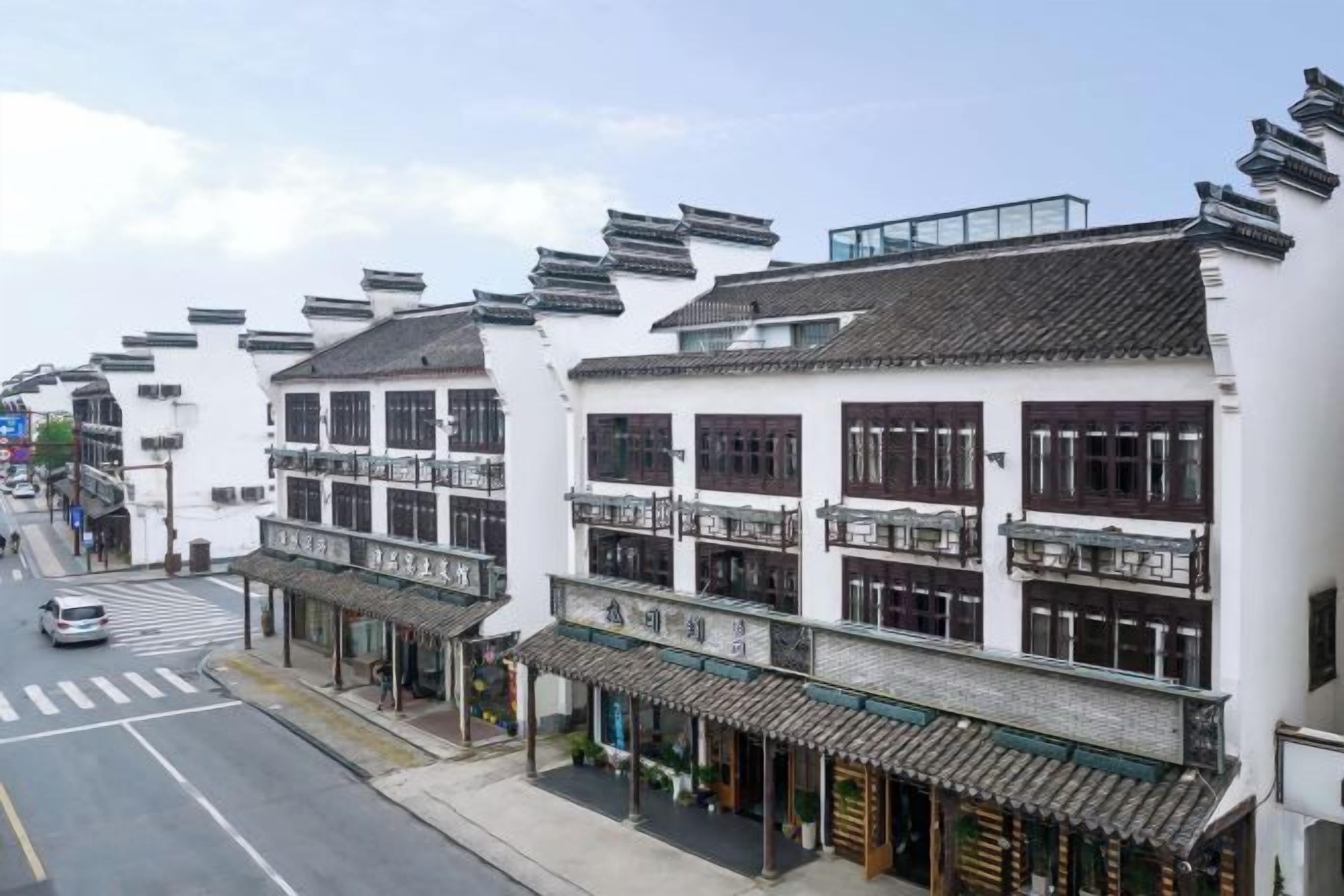 Una hilera de edificios blancos tradicionales con varios pisos, balcones y una calle en primer plano.