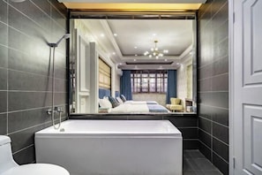 A modern bathroom with a large bathtub, a shower, and a view into a bedroom with a bed and a window. - Wuzhen Xizha Jiurige Homestay (Tongxiang)
