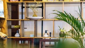 A wooden shelf with various items including a plant, a bottle, and a small vase.