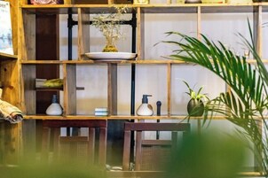 Una repisa de madera con varios objetos, entre ellos una planta, una botella y un jarrón pequeño.