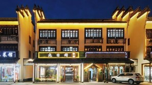 A multi-story building with illuminated signage and storefronts at night.