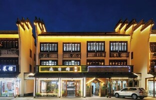Un edificio de varios pisos con letreros iluminados y escaparates de tiendas por la noche.