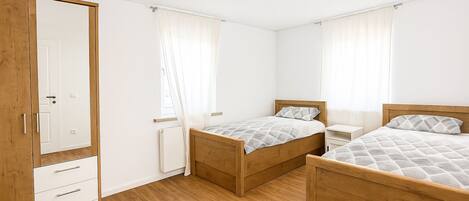 A bedroom with two wooden beds, a wardrobe, and a radiator.