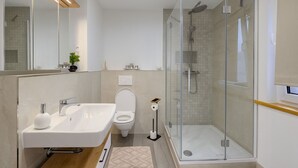 Un bagno moderno con cabina doccia in vetro, un lavandino bianco e un water.