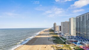 Vista de la playa con arena, océano y edificios altos.