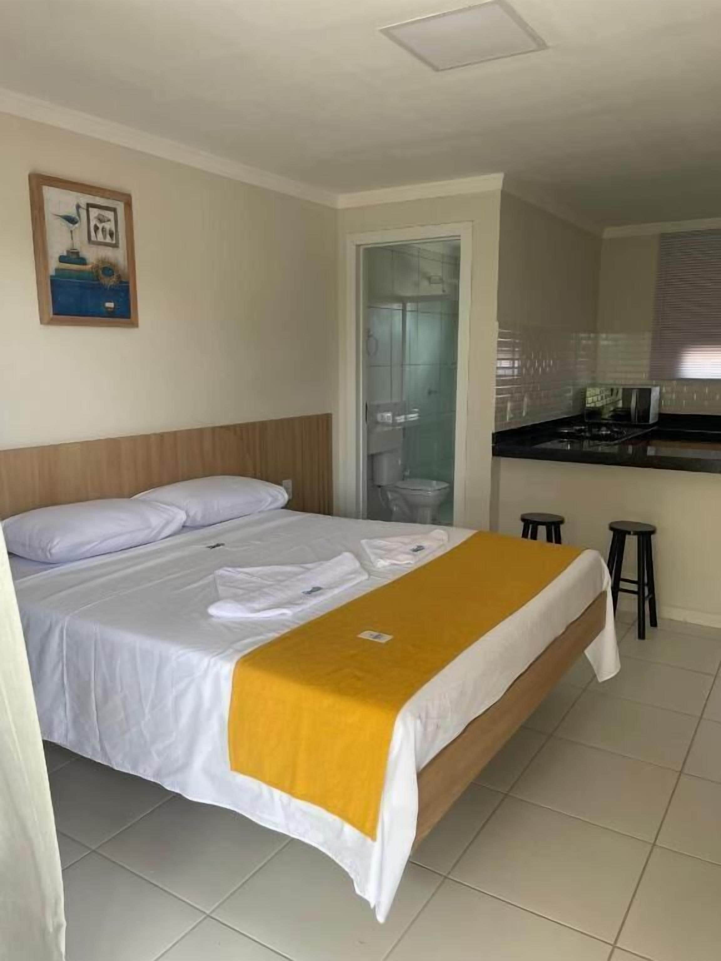 A hotel room with a bed, a bathroom, and a kitchenette.