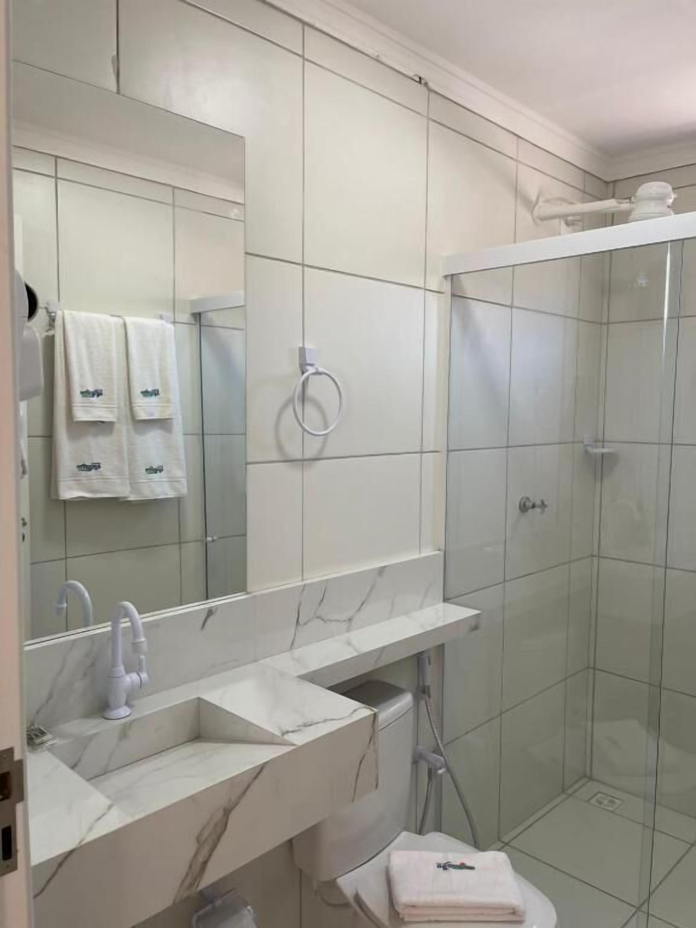 Une salle de bain avec un lavabo blanc, un miroir et une douche.