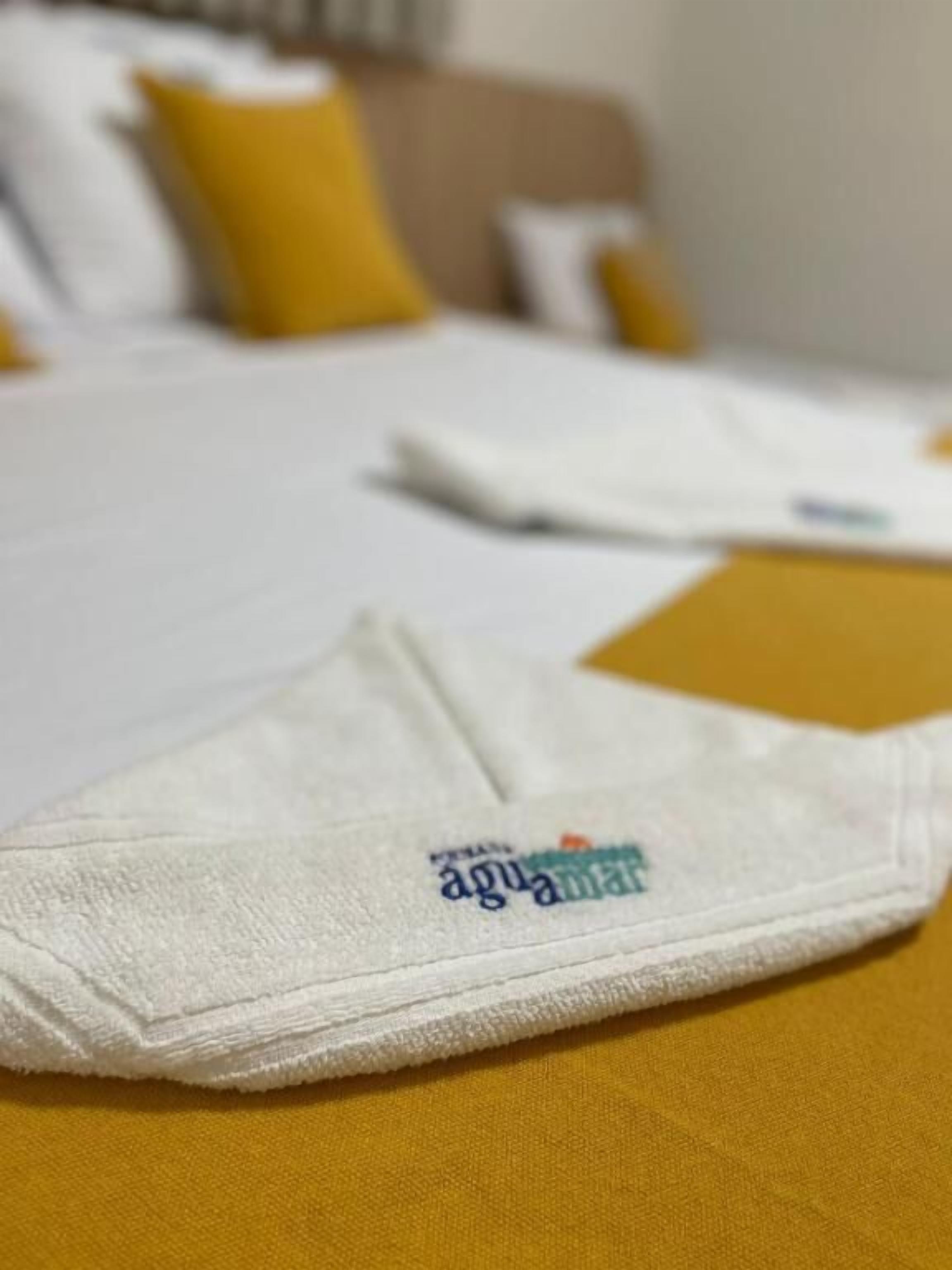 Una cama con ropa blanca y una almohada amarilla.