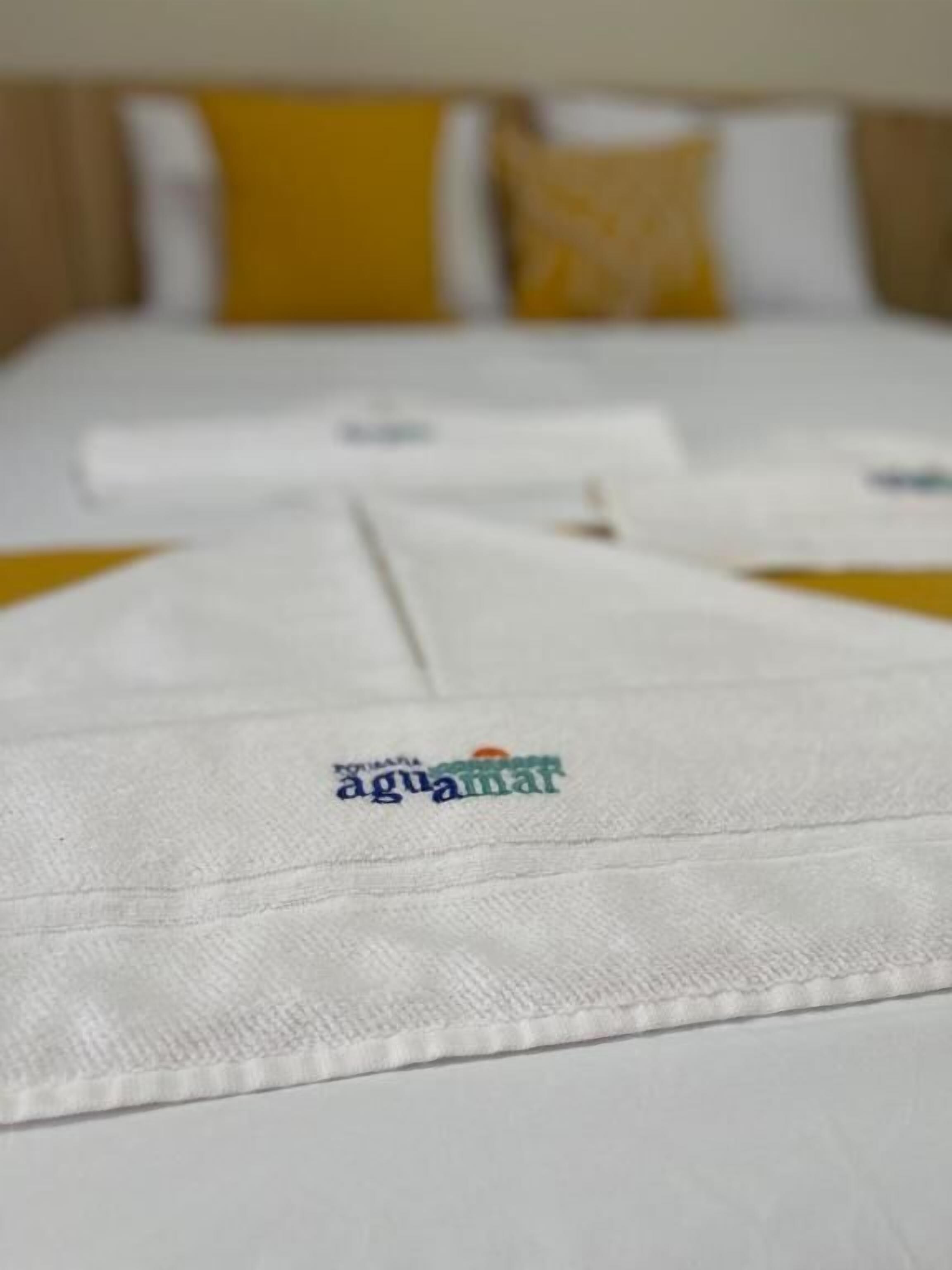 A bed with white bedding and a pillow with a yellow accent.