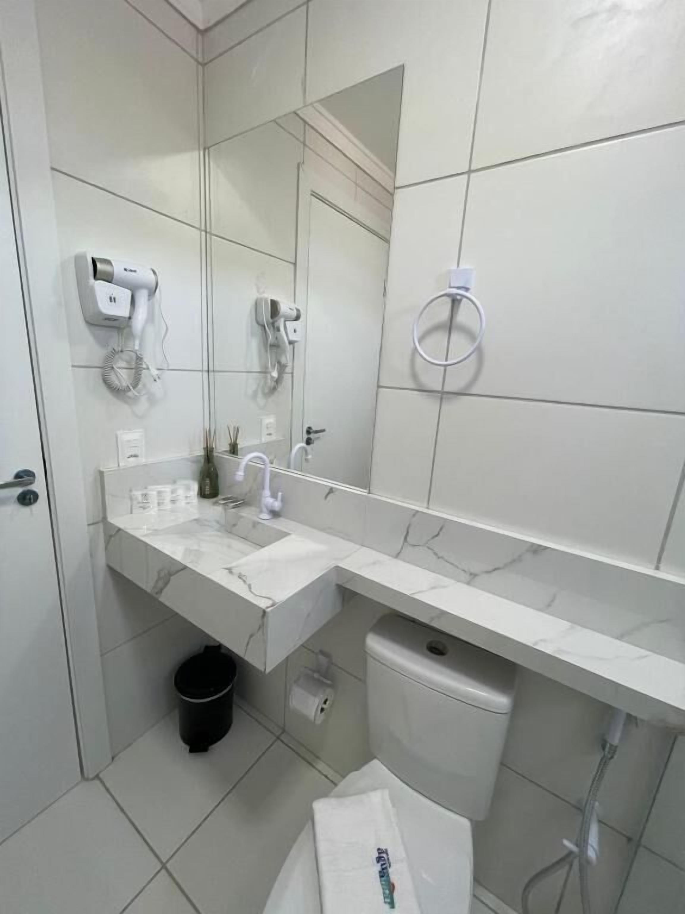 Une salle de bain moderne avec un lavabo blanc, un miroir et un porte-serviettes.