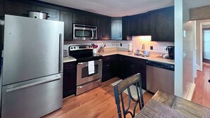 A compact kitchen with a refrigerator, microwave, stove, and sink. - Newly refreshed four bedroom, three full bath multilevel condo (Sugar Mountain)