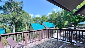 A wooden deck with metal chairs, a railing, and a view of a building with a green roof. - Newly refreshed four bedroom, three full bath multilevel condo (Sugar Mountain)