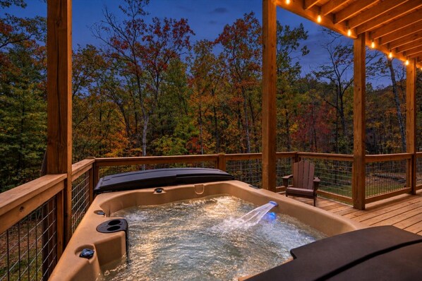 A hot tub on a wooden deck with a view of autumn trees.