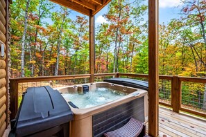 Un bain à remous sur une terrasse en bois, avec vue sur les arbres aux couleurs automnales.
