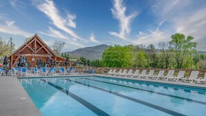 A swimming pool with lounge chairs and umbrellas, a wooden cabin, and a mountainous backdrop. - 2BR w/Hot Tub*Fireplace, MTN View, Community Pool! (Sevierville)