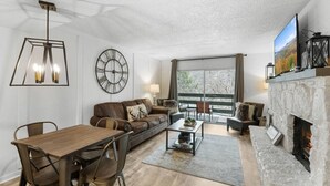 Una sala de estar moderna con chimenea, comedor y un ventanal con vistas.