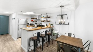 Una cocina moderna con una isla central, taburetes de bar y una mesa de comedor.