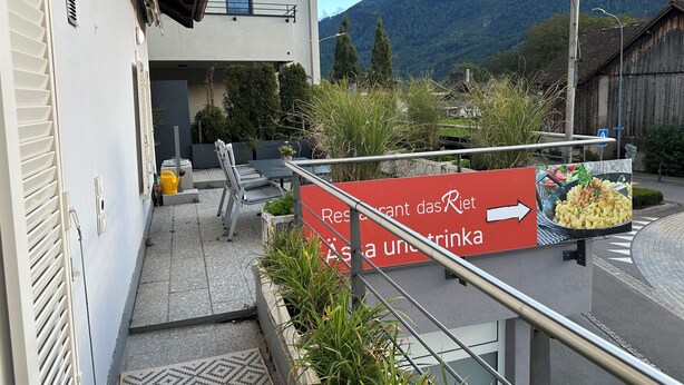 Une enseigne de restaurant indiquant la présence de tables en plein air et offrant une vue sur la montagne.
