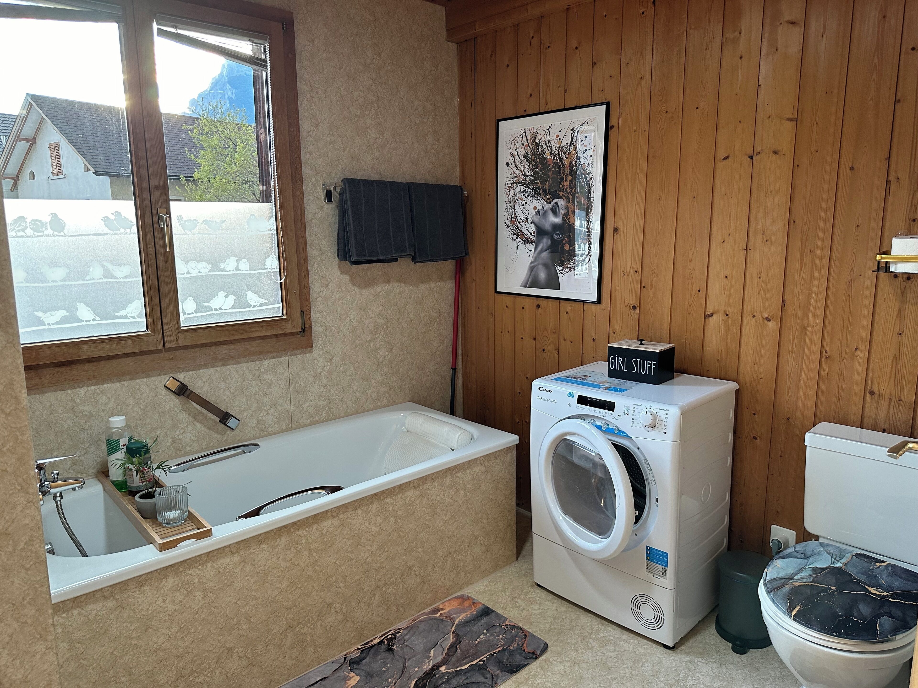 A bathroom with a bathtub, a washing machine, and a toilet.