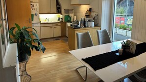 Une cuisine moderne avec des meubles en bois, une table à manger avec des chaises et une grande fenêtre donnant sur l’extérieur.