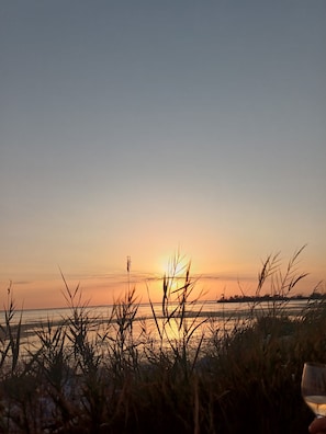 A sunset view with a body of water and grass in the foreground. - "An Endless Summer"! Apartment with a courtyard, a 5-minute walk from the beach (Saintes-Maries-de-la-Mer)