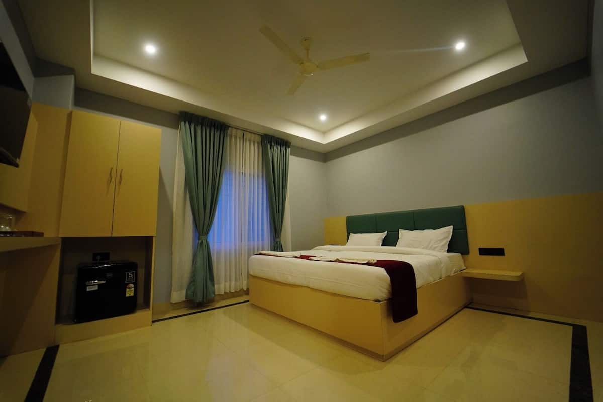 Una habitación de hotel moderna con una cama grande, un ventilador de techo y una mesita de noche pequeña.