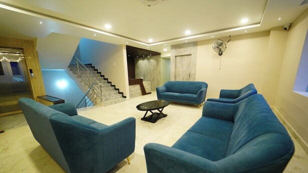 Un salón espacioso con un amplio sofá seccional azul, una pequeña mesa de centro y una escalera que sube a un piso superior.