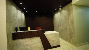 Una recepción con panel de madera oscura, paredes de mármol e iluminación empotrada.