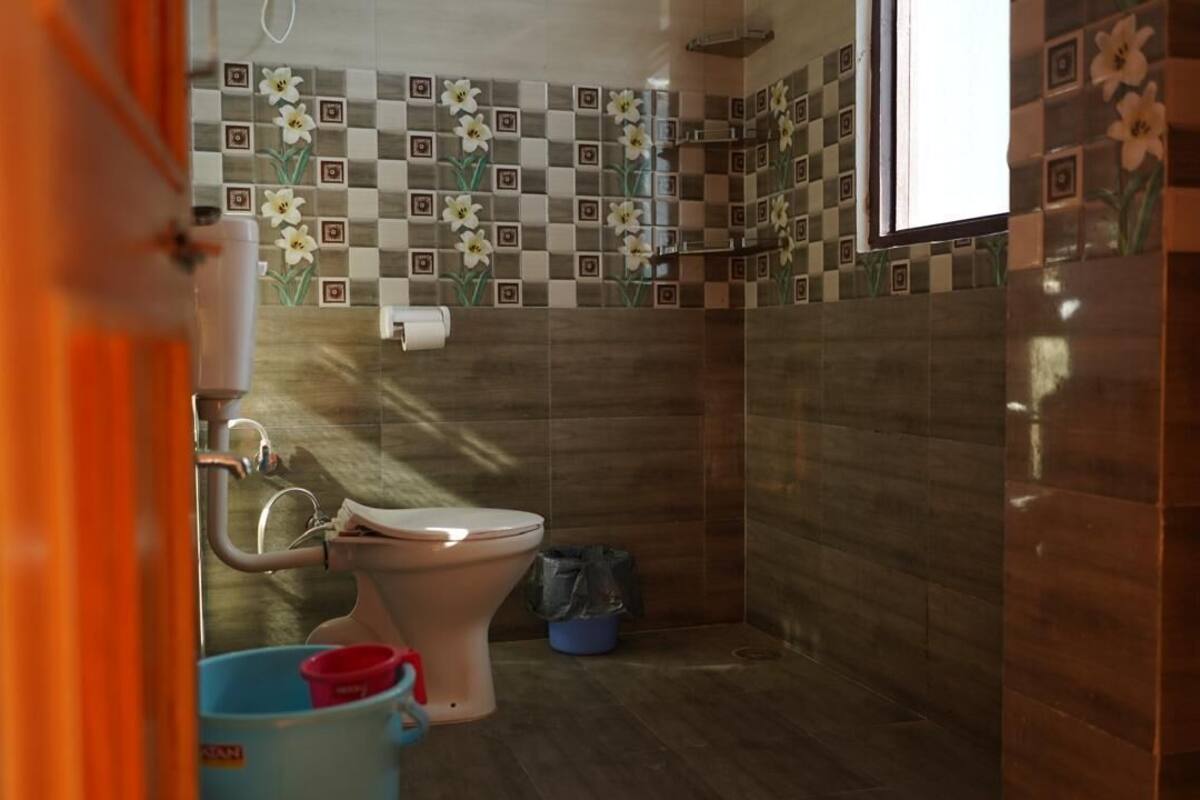 A bathroom with a toilet, a sink, and a shower. The walls are tiled with a floral pattern.